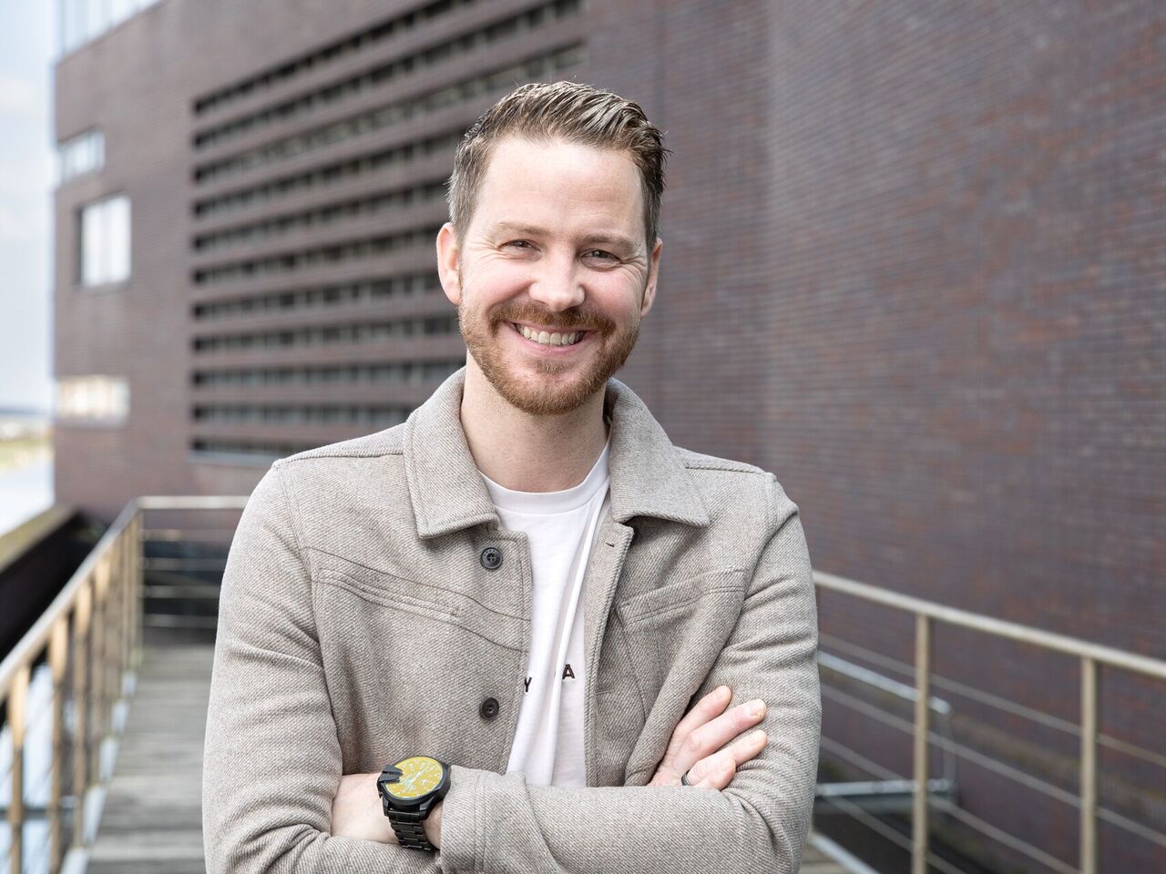 Collega staat lachend buiten op de foto. 