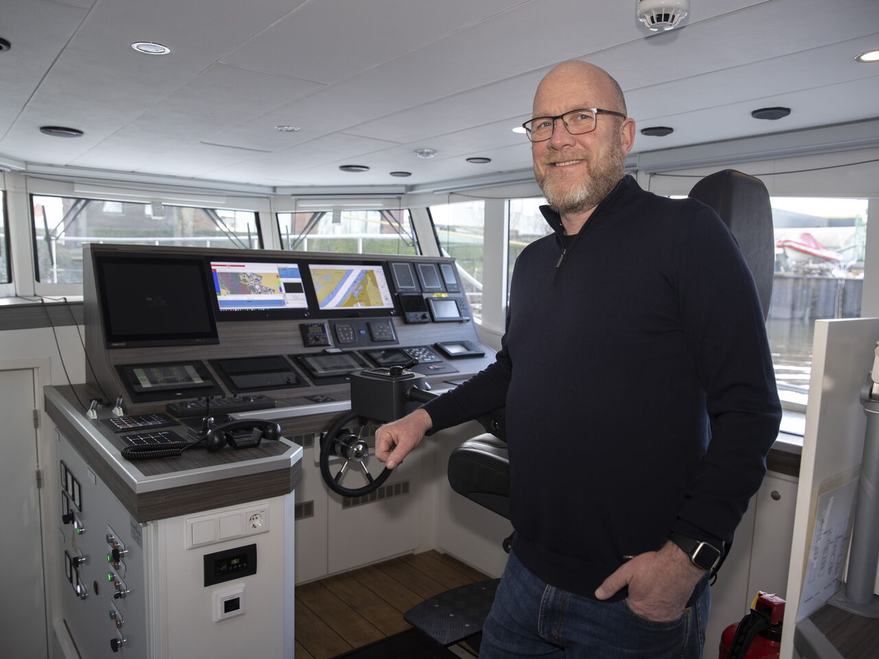 Een collega staat lachend op de foto op de boot. 