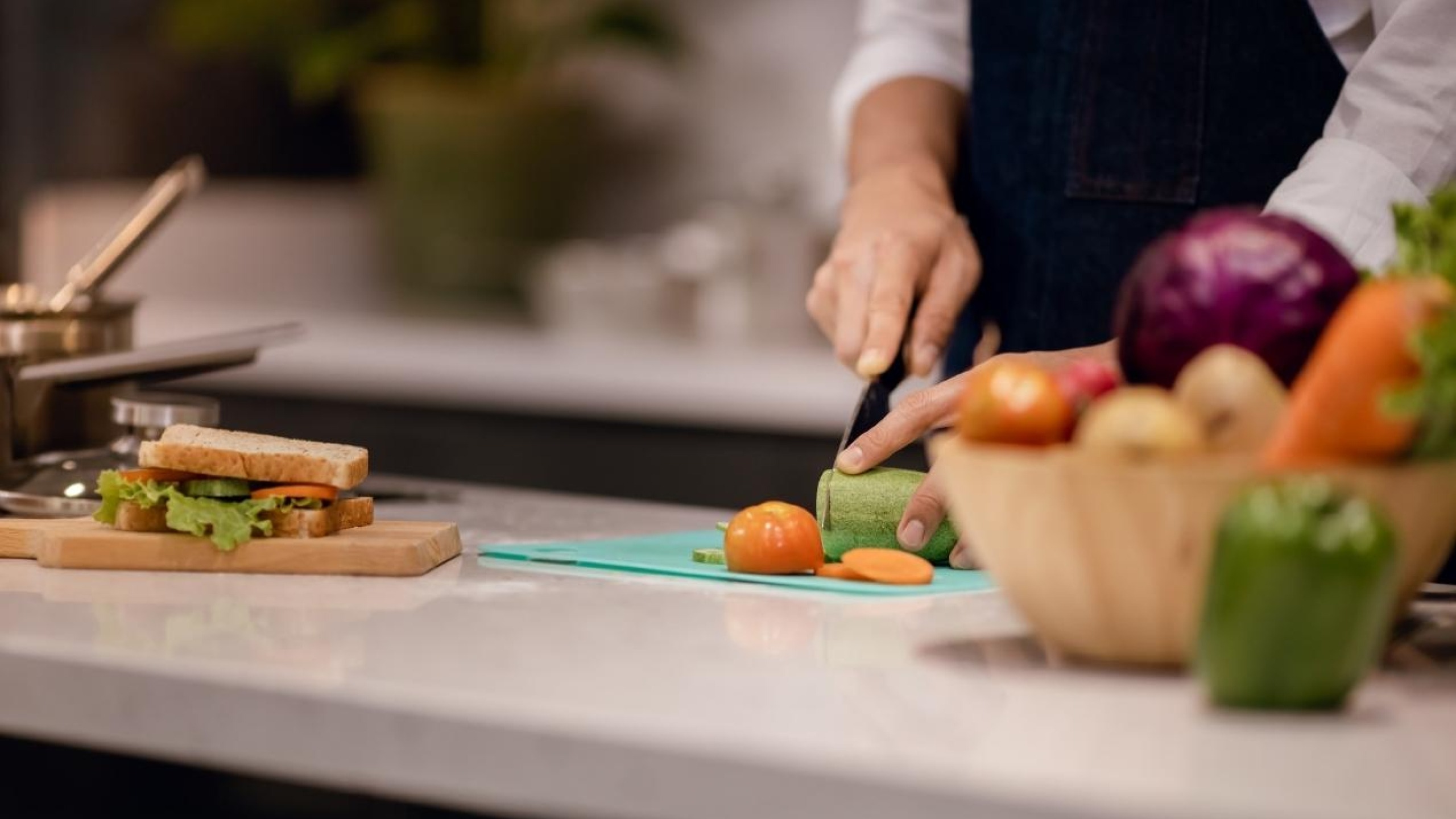 Persoon staat groente te snijden in een keuken.