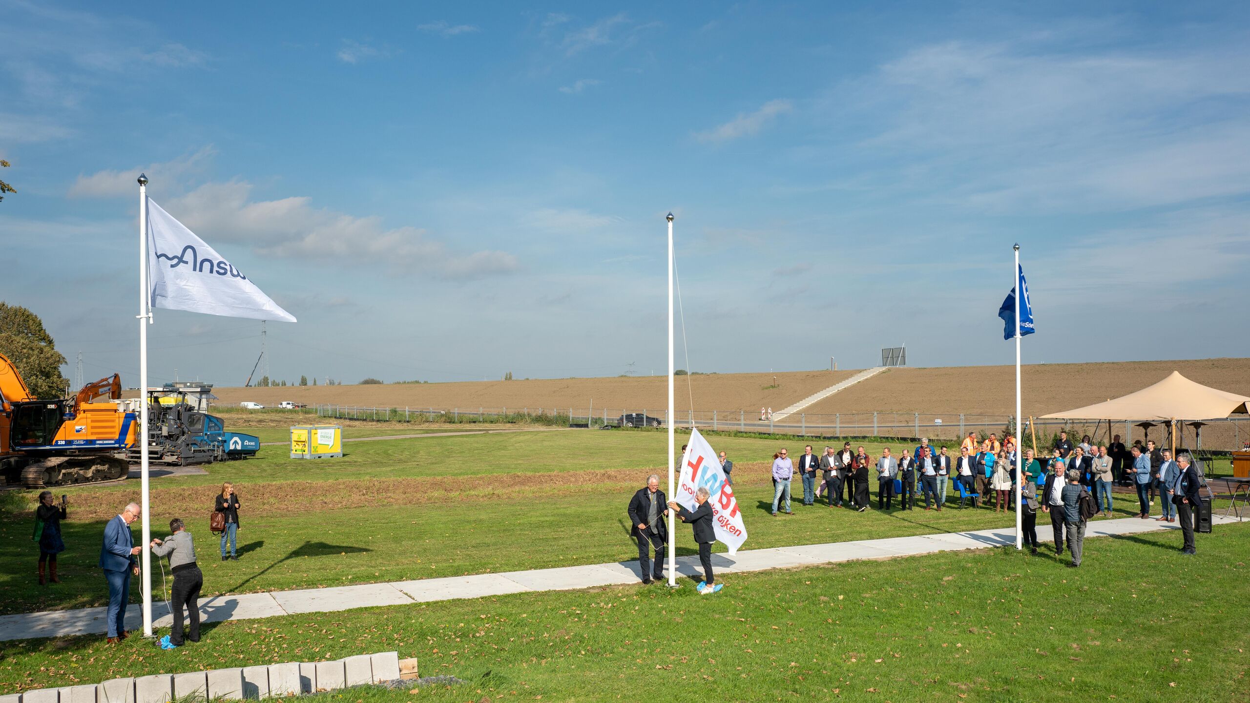 Vlaggen worden gehesen bij de opening van het informatiecentrum bij dijkversterking Hansweert.