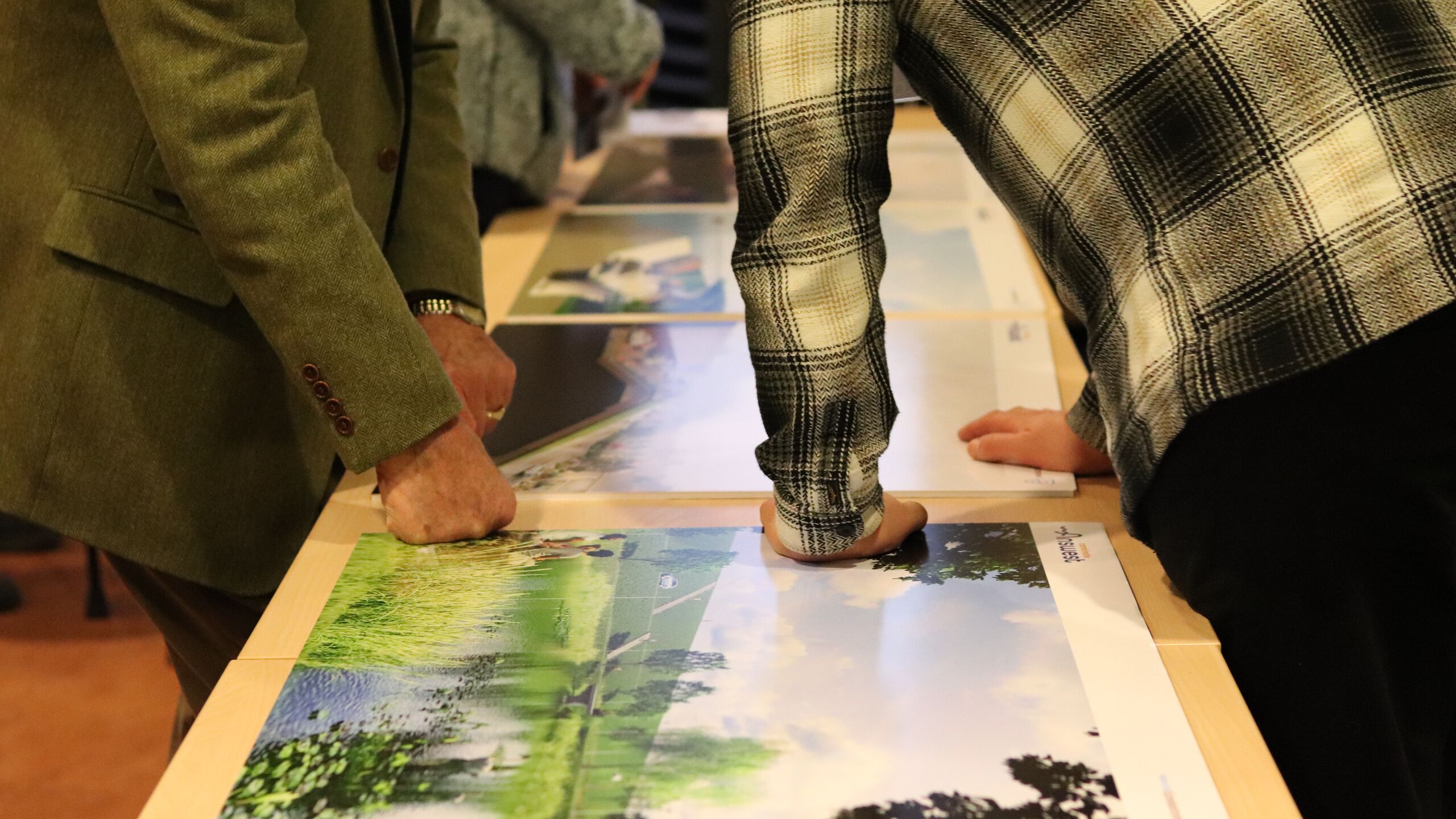 weergave van de inloopavond. bezoekers in het dorpshuis bekijken de visualisaties en krijgen uitleg