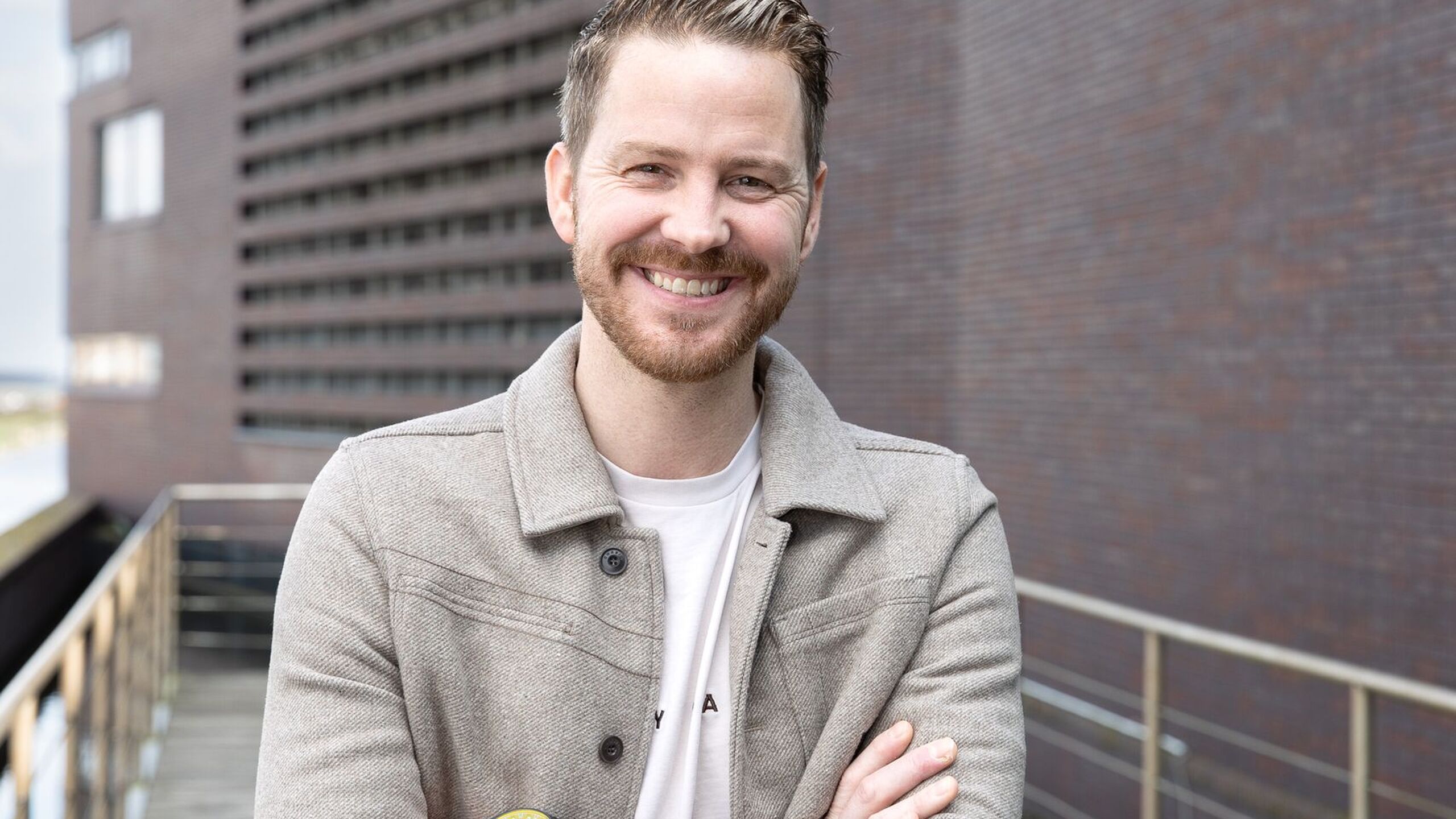 Collega staat lachend buiten op de foto. 