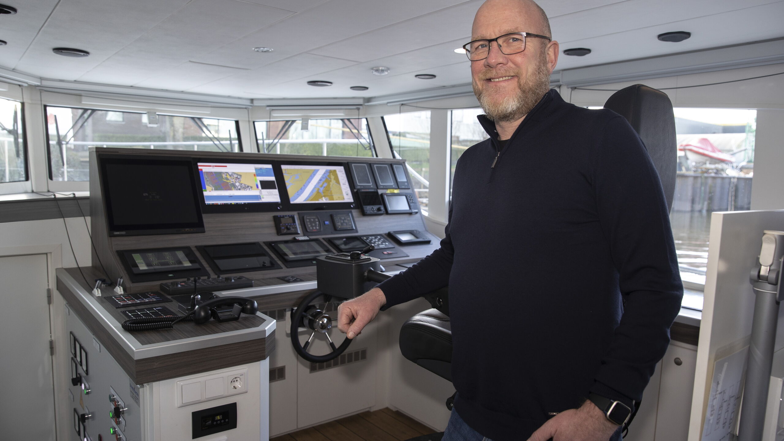 Een collega staat lachend op de foto op de boot. 
