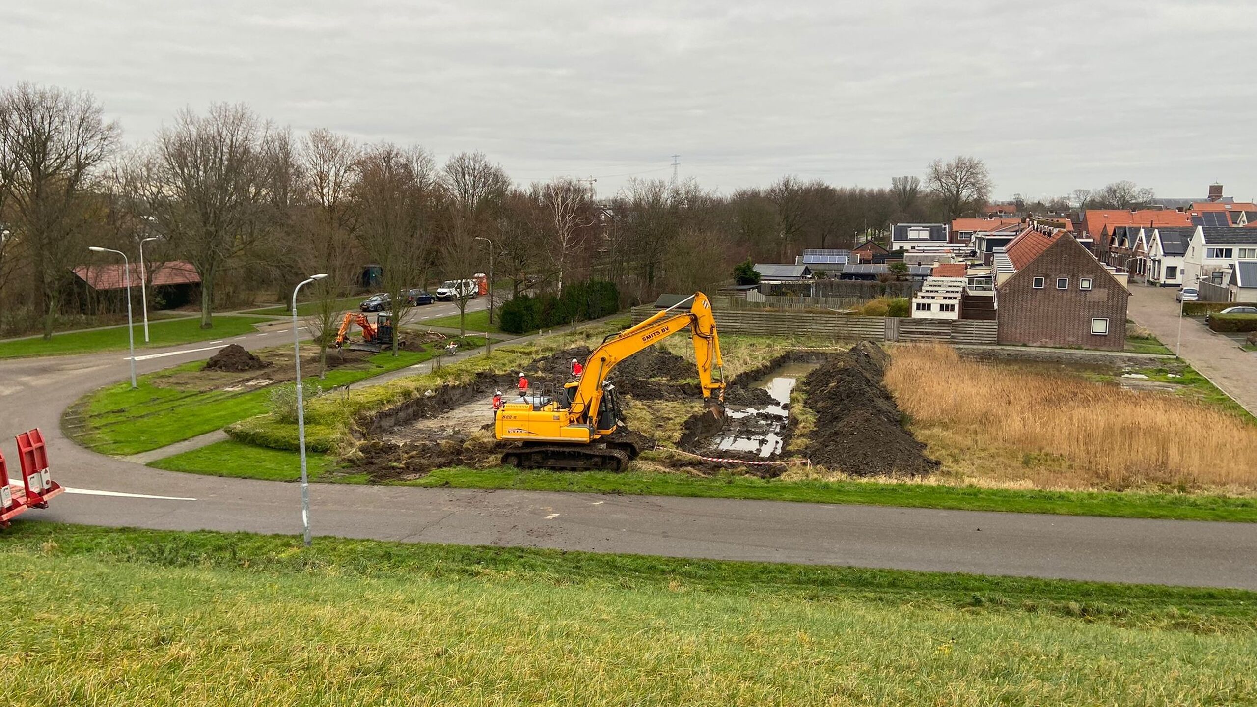 Een graafmachine maakt proefsleuven bij dijkversterking Hansweert.