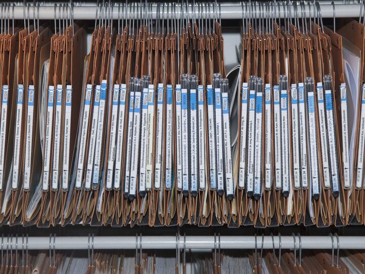 Een rij archiefmappen in een archiefkast.