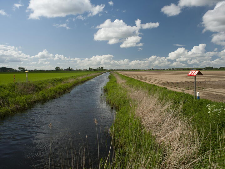 Een sloot langs landbouwgrond.