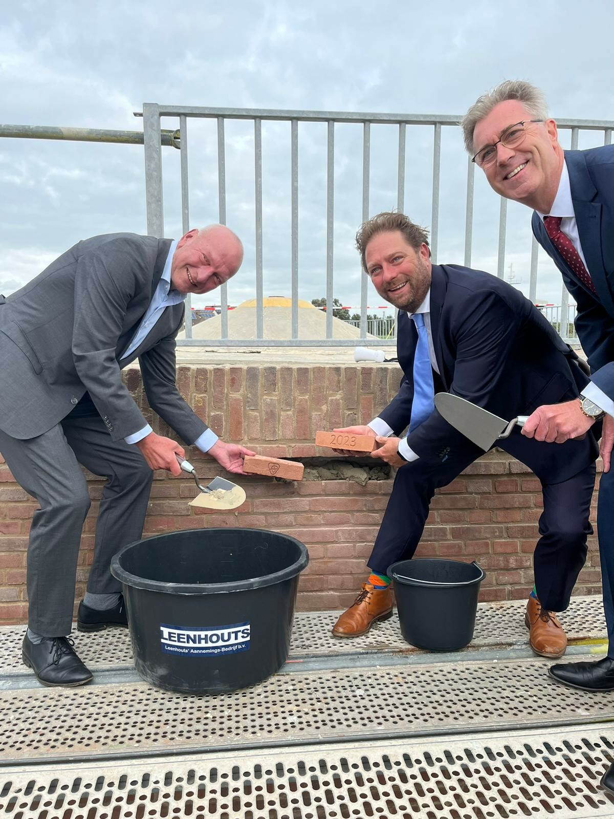 Drie heren leggen sympbolisch de laatste steen bij de gerestaureerde Muur van Altena.