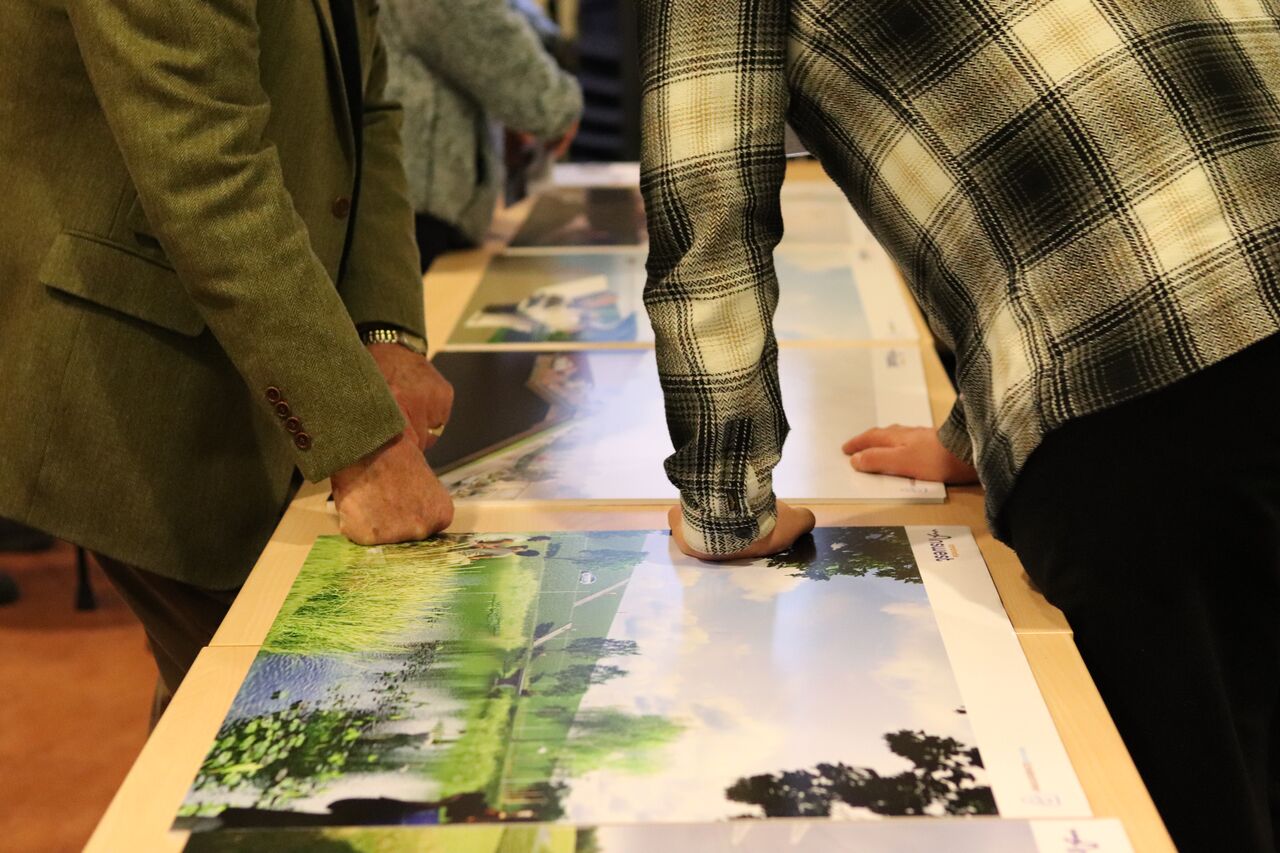 weergave van de inloopavond. bezoekers in het dorpshuis bekijken de visualisaties en krijgen uitleg