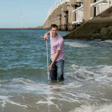 Collega Jelle-Jan staat in de zee met een meetlint in zijn handen.