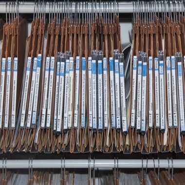 Een rij archiefmappen in een archiefkast.