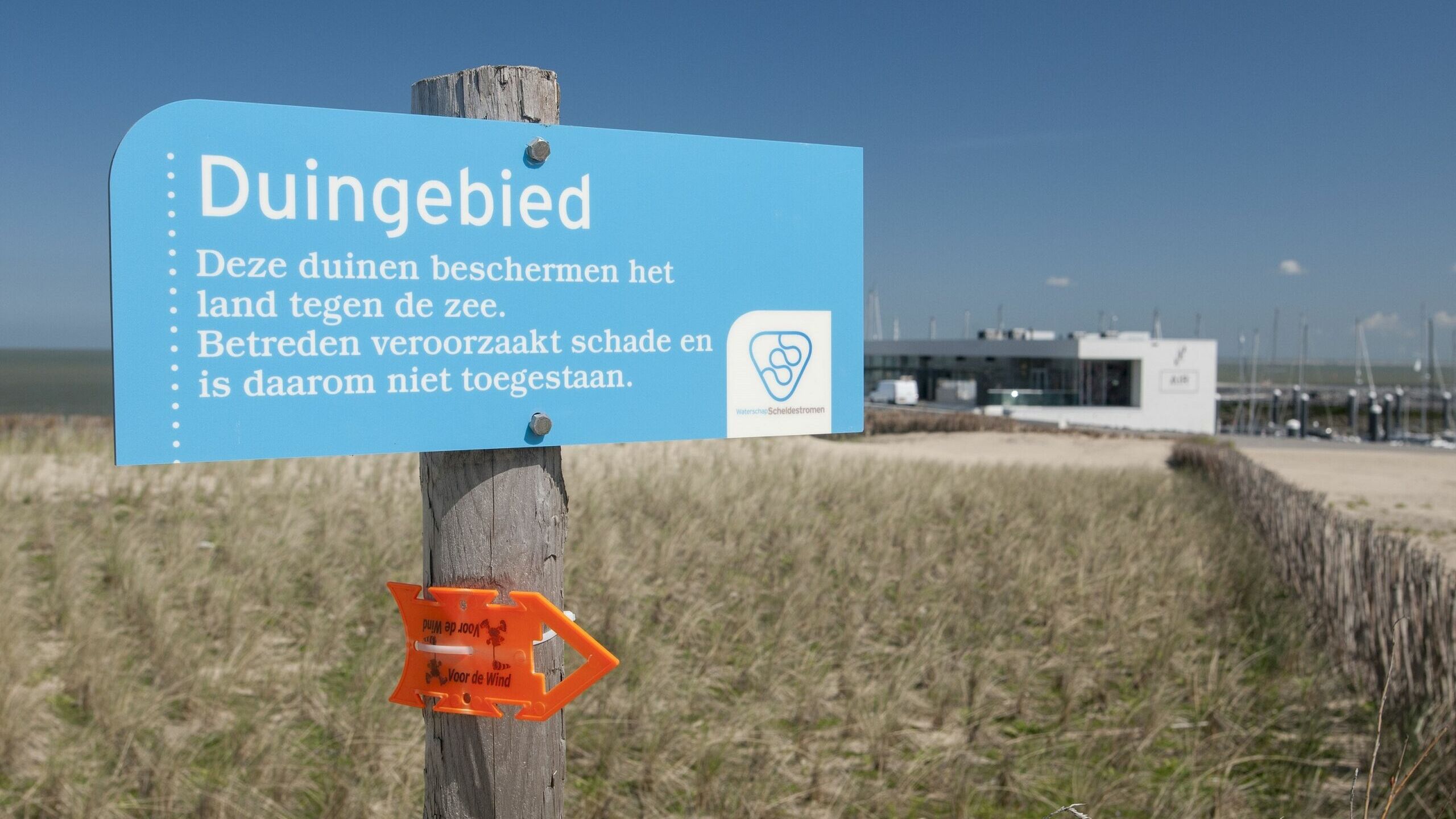 Een bordje bij de duinen waarop staat dat toegang tot het duingebied verboden is.